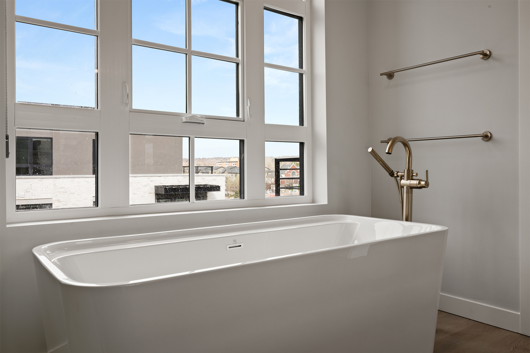 Freestanding soaking tub in a Sugar Alley penthouse bathroom with large picture windows and natural light.