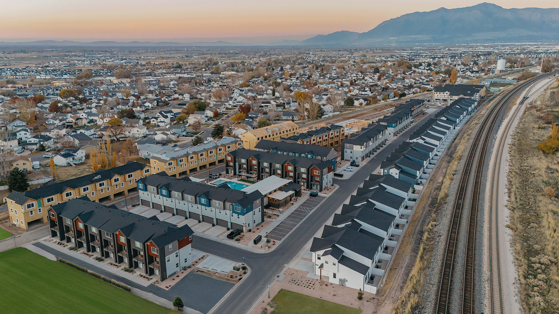 Aerial view of Railrunner townhomes in Roy, Utah, with the FrontRunner rail tracks running alongside the community.