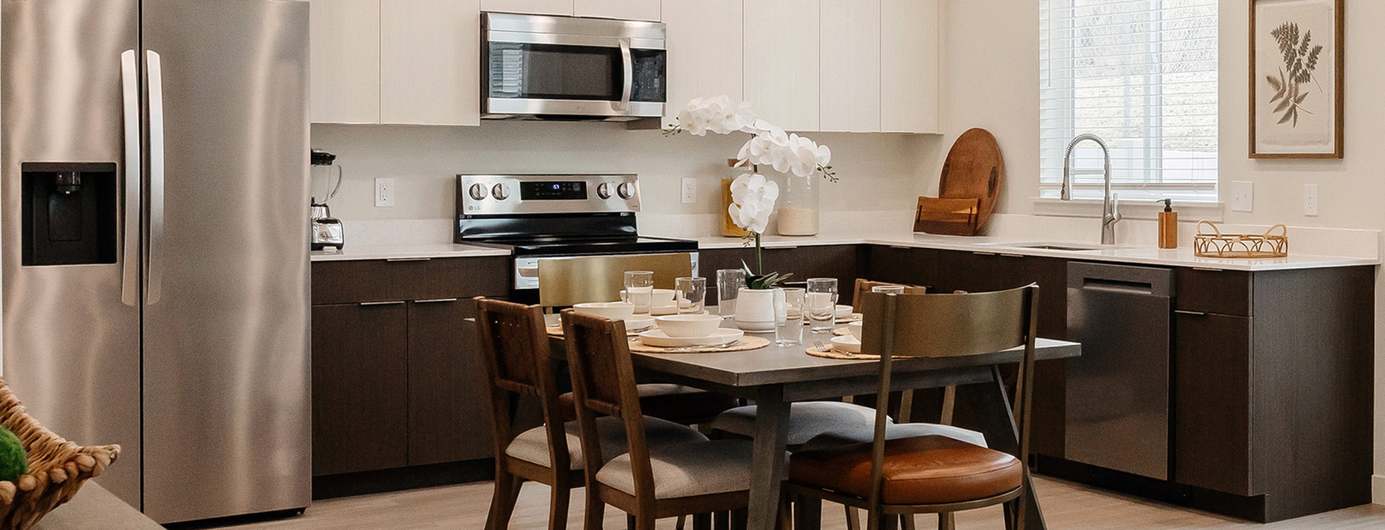 Modern kitchen with stainless steel appliances and dining table inside a Railrunner townhome in Roy, Utah.
