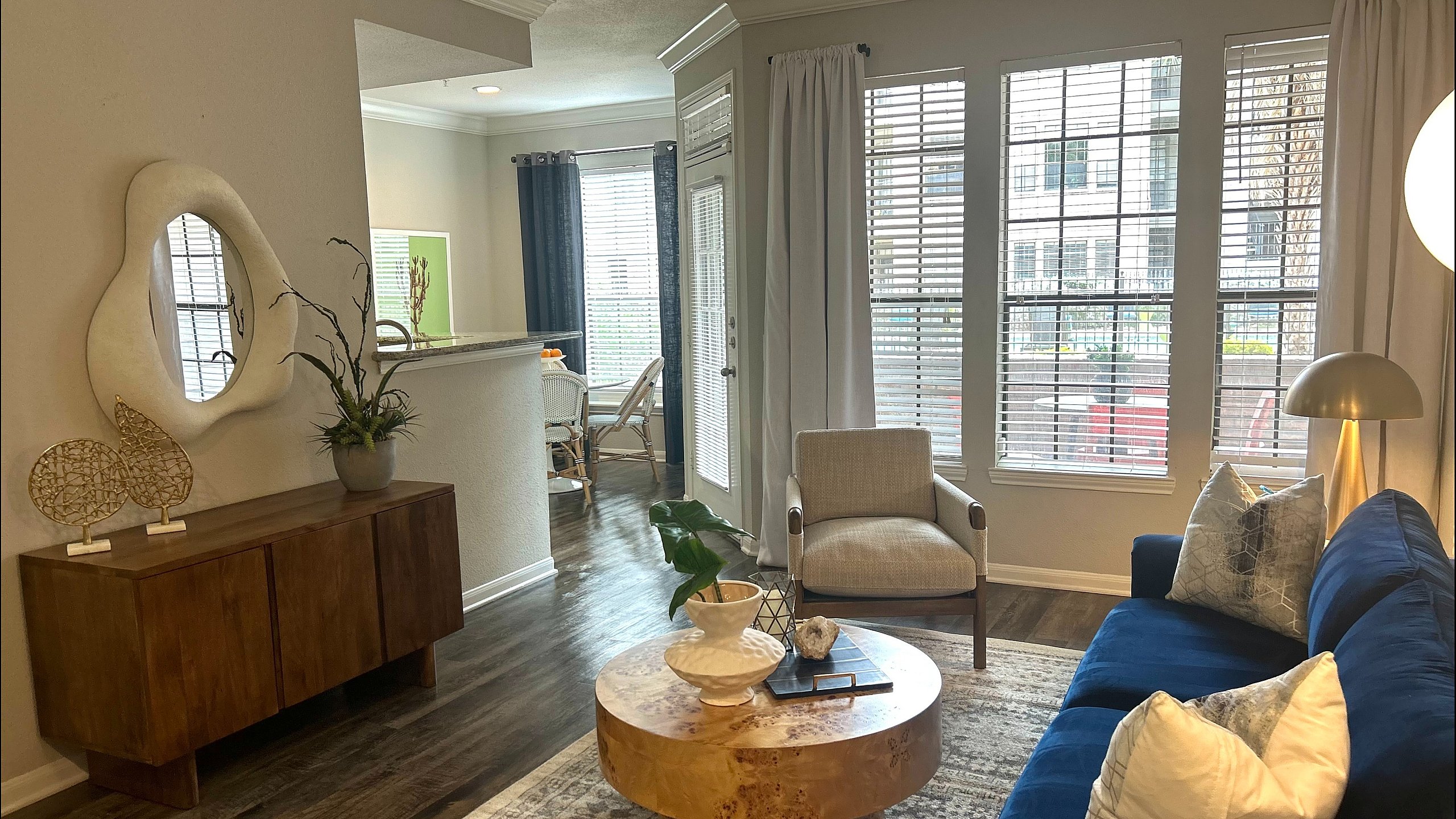 Elegant living room with a plush blue sofa, modern decor, and abundant natural light from large windows.