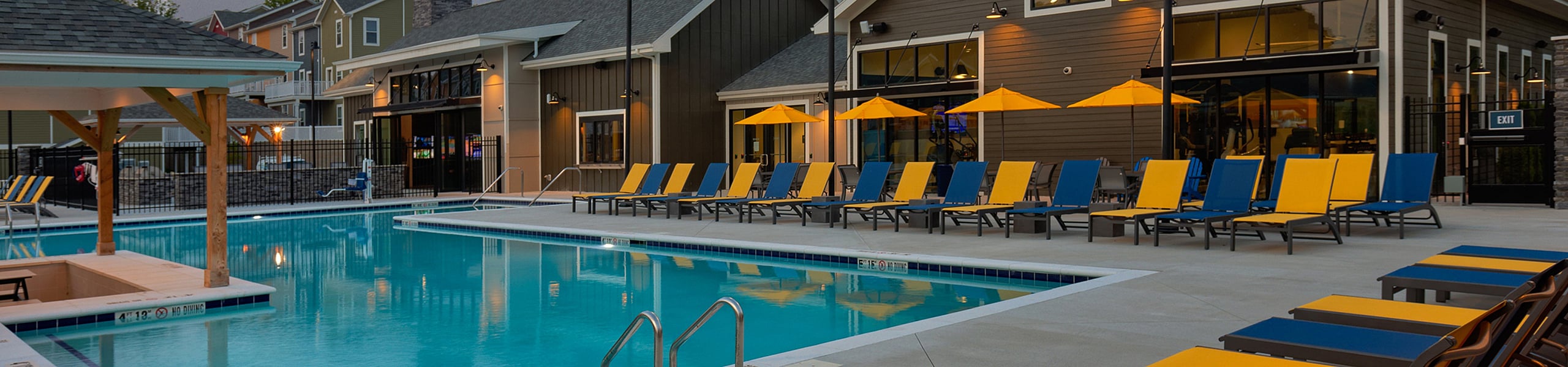 Luxurious poolside retreat with vibrant loungers and modern clubhouse, offering a relaxing oasis for residents.