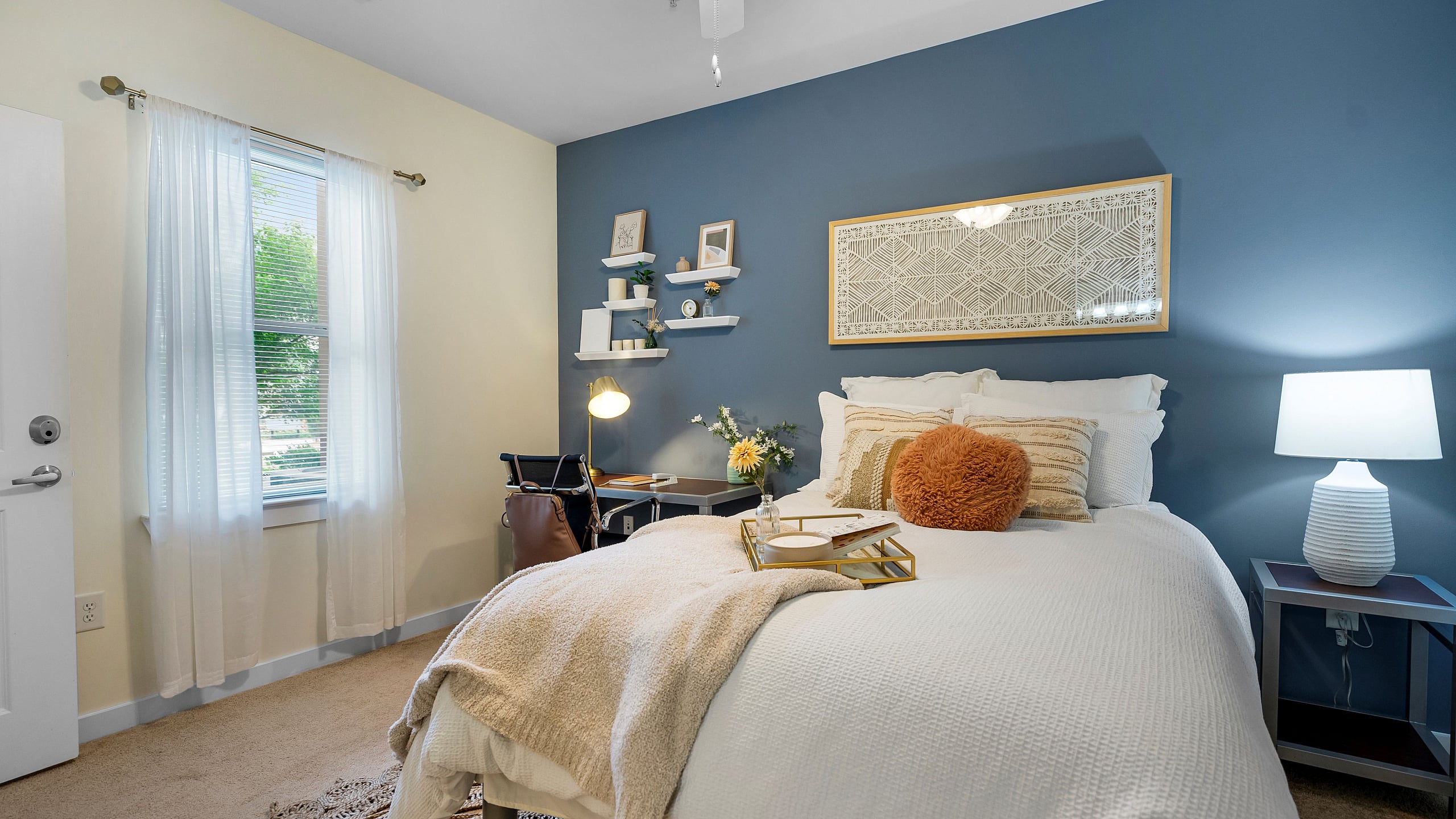 campus crossings briarcliff 2 bedroom model unit with full sized bed, desk, and end table.