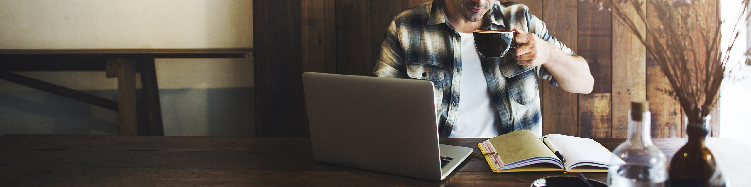 Cozy workspace with a laptop and open journal, perfect for creative inspiration or remote work, complemented by a cup of coffee and rustic decor.