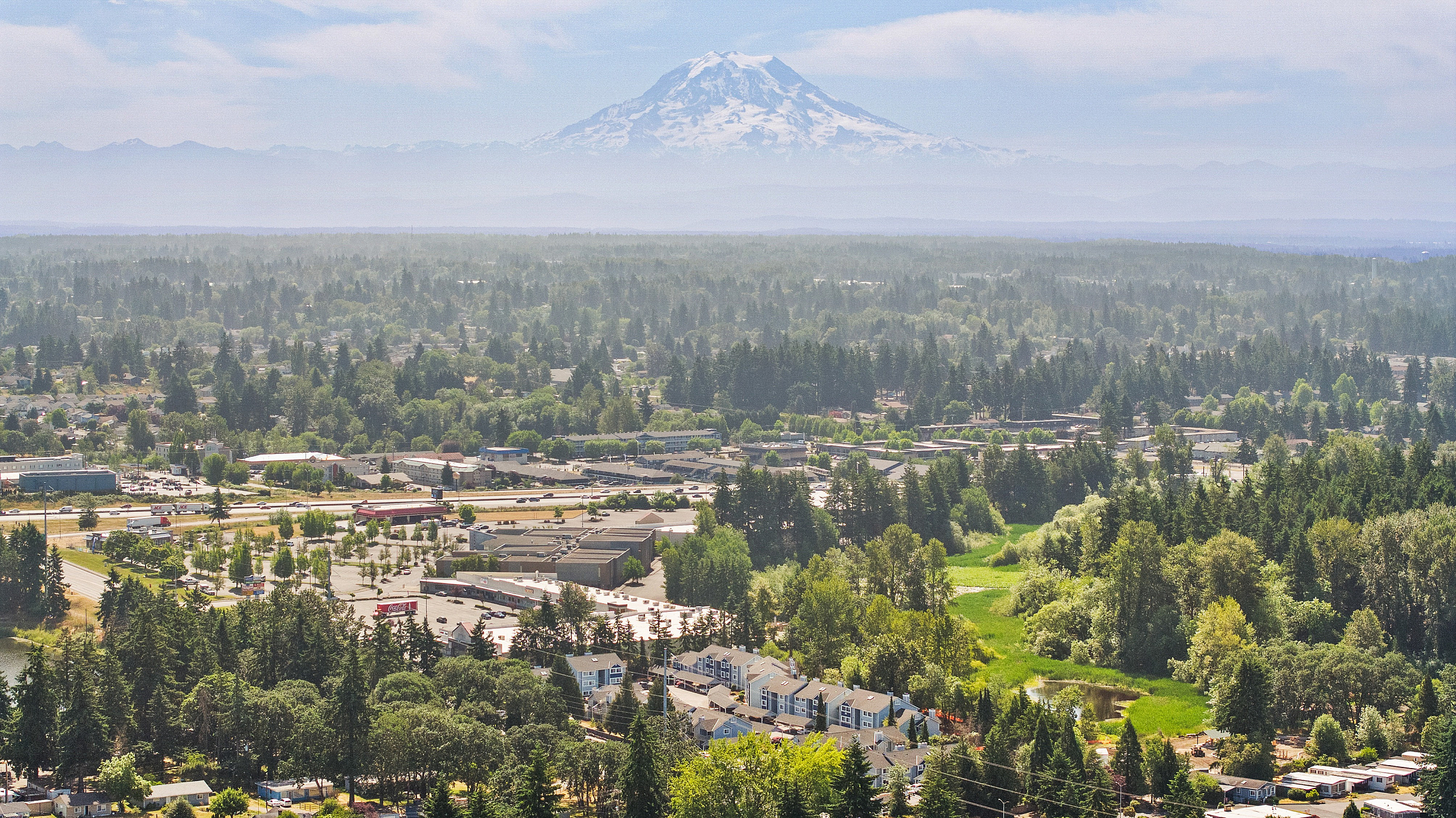 Breathtaking aerial view of a vibrant community nestled among lush greenery with majestic mountain backdrop.