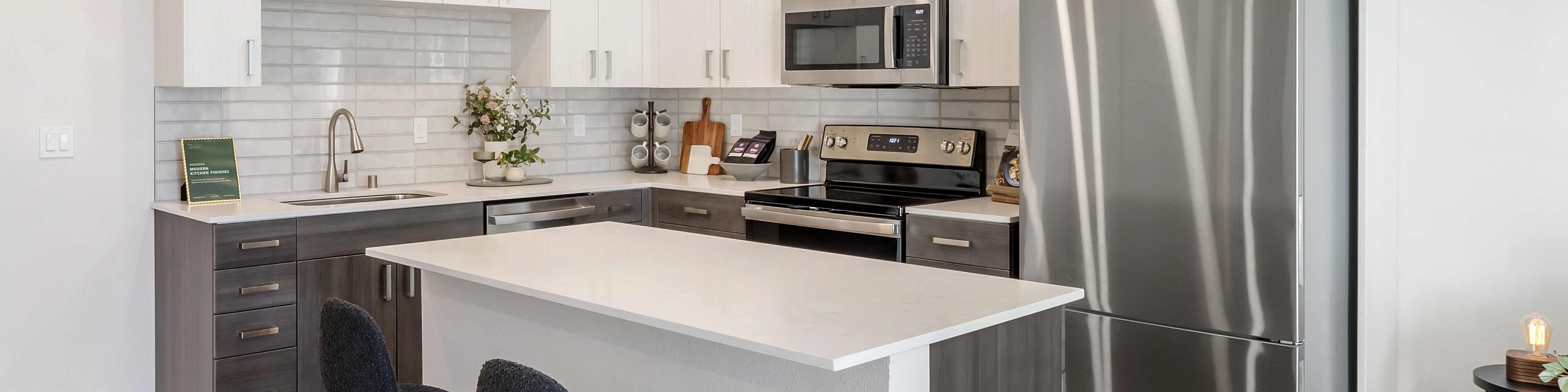 Modern kitchen within The Edison in Reno, NV including sleek stainless steel appliances, elegant cabinetry, and a chic island with stylish seating.