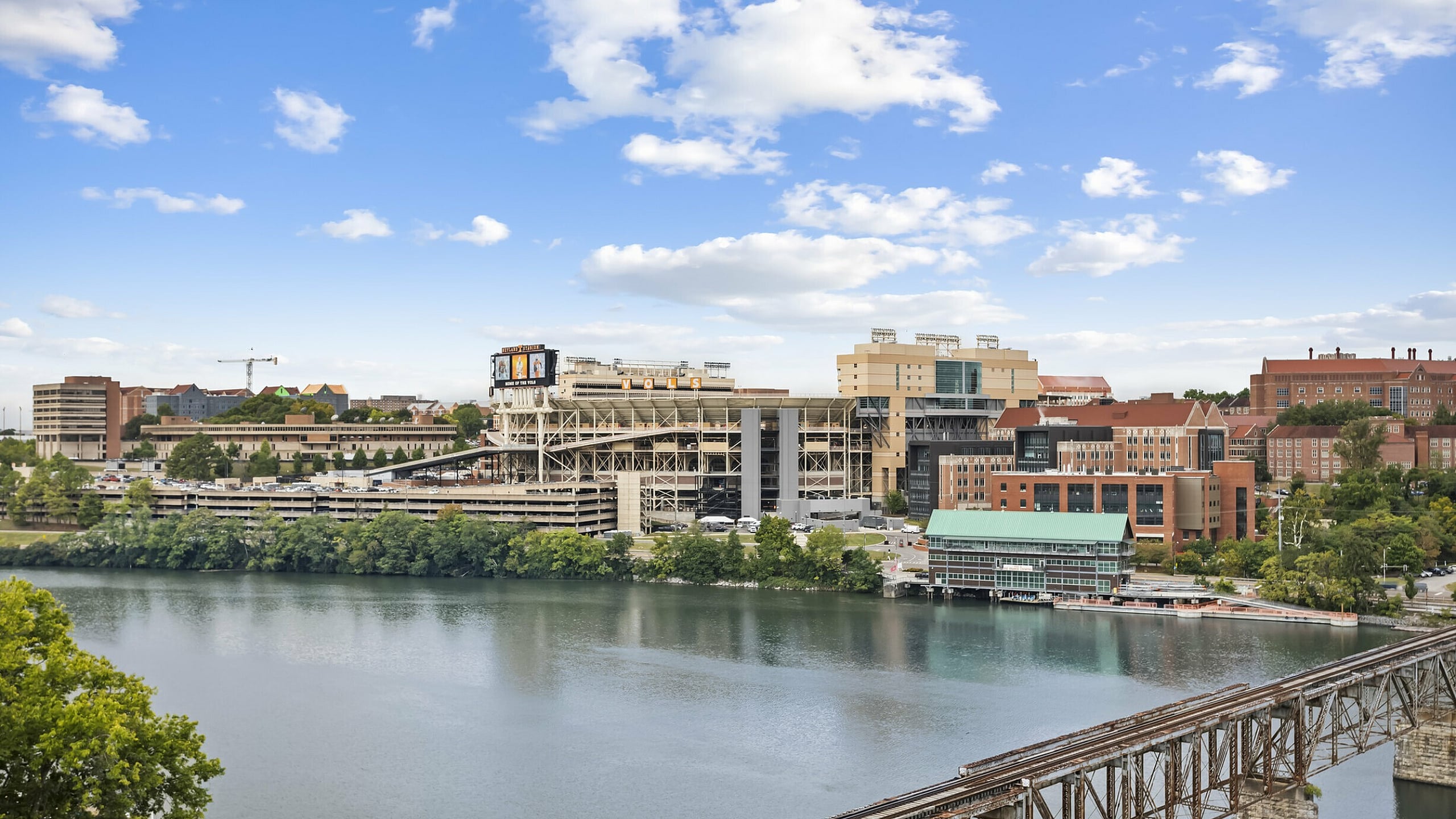 Scenic Tennessee River view showcasing a vibrant Knoxville cityscape with modern architecture and a prominent stadium under a bright blue sky.