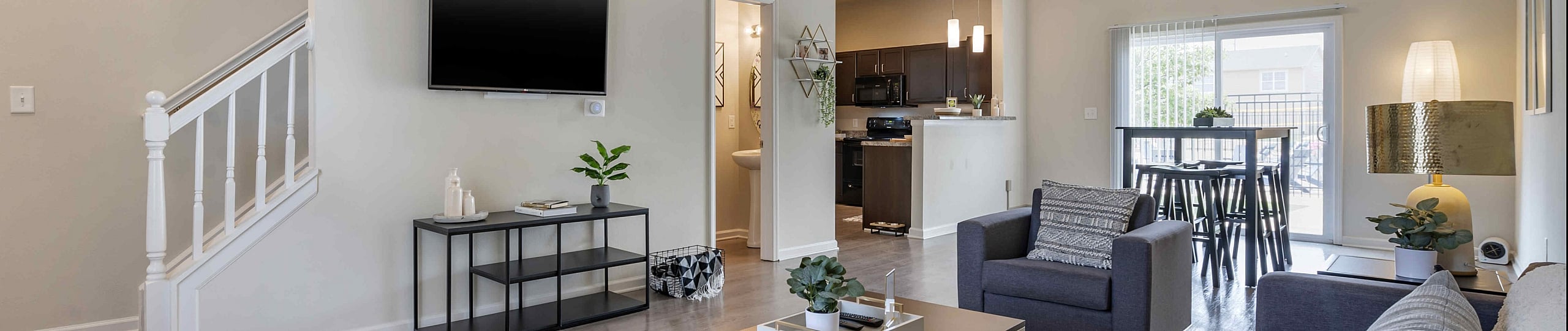 Modern open-concept living room featuring cozy seating, chic decor, and natural light flowing through sliding glass doors to a spacious balcony.