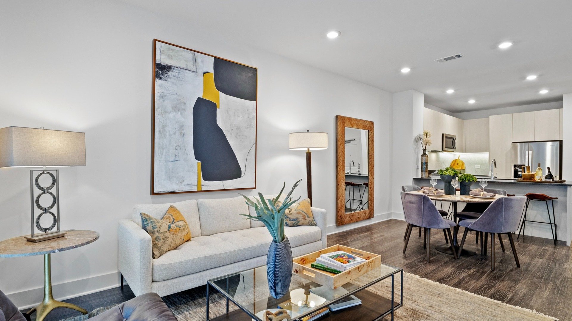 Living room with couch and coffee table with kitchen and dining room in background