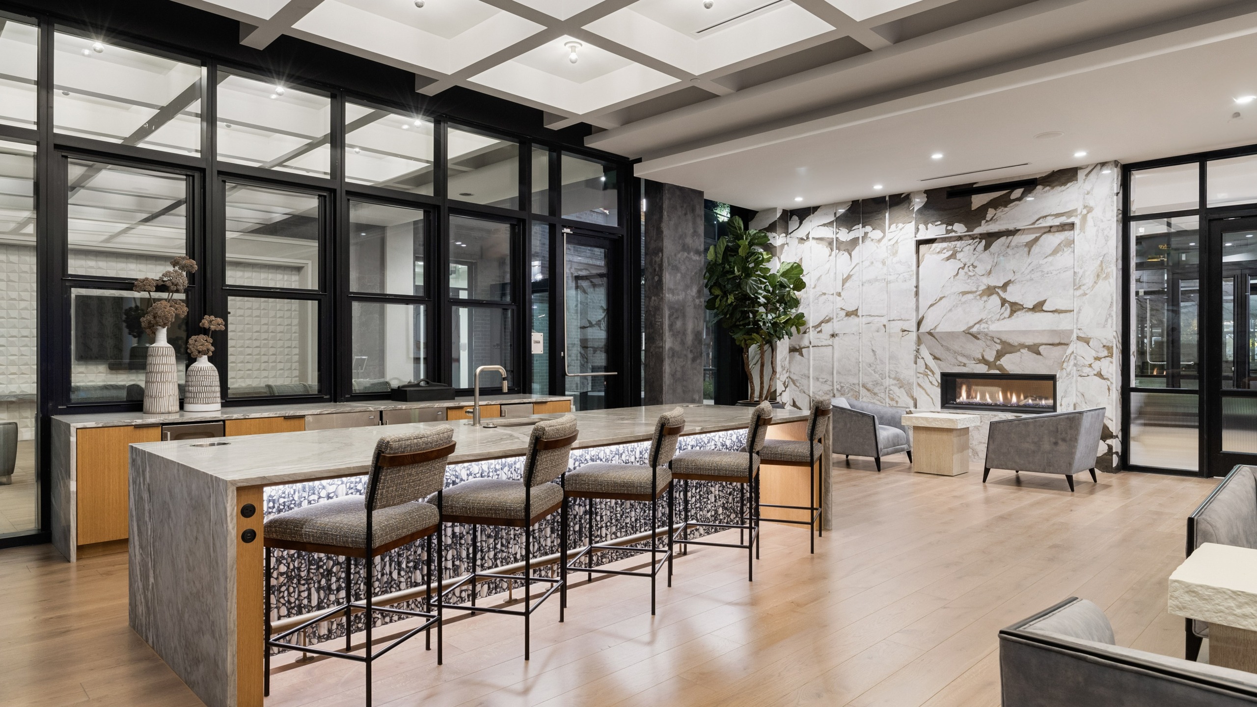 entertaining room with counterheight island with chairs next to a feature fireplace with seating