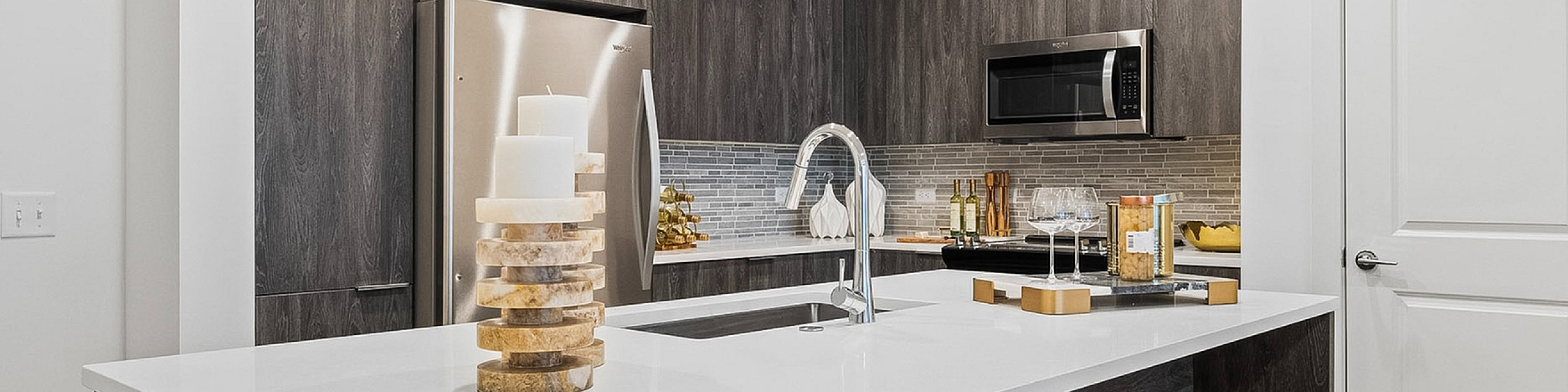 Stylish kitchen with sleek wooden cabinets, contemporary island with seating, stainless steel appliances, and elegant decor accents.