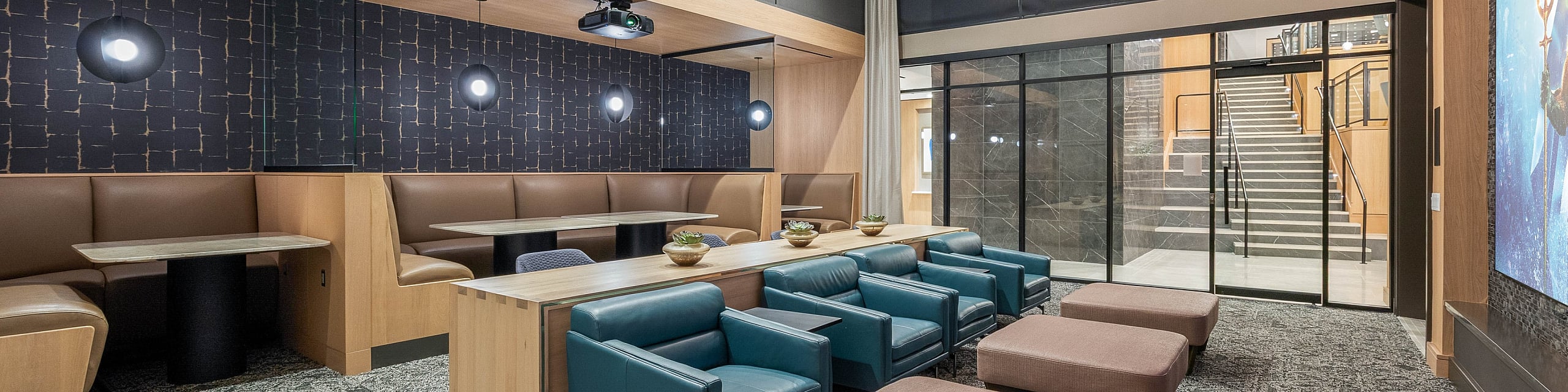 Contemporary entertainment lounge featuring plush seating, stylish booths, and a large projector screen, ideal for social gatherings.