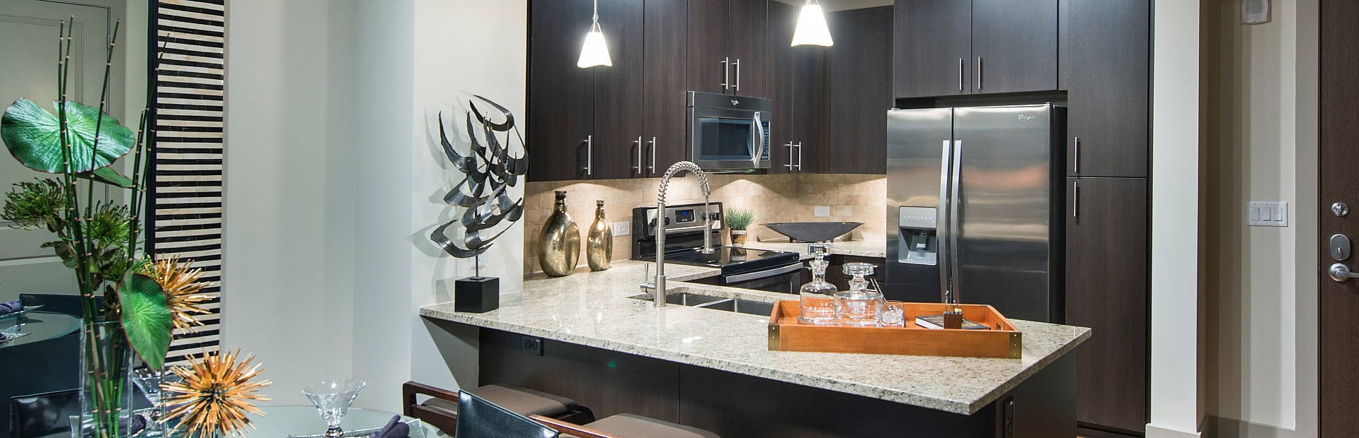 Elegant kitchen and dining area with modern dark wood cabinetry, sleek granite countertops, and contemporary lighting.