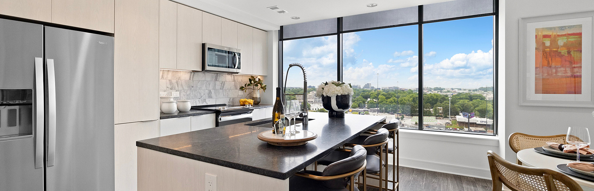 Modern kitchen with sleek appliances, elegant island, and stunning panoramic window views, ideal for luxurious living.