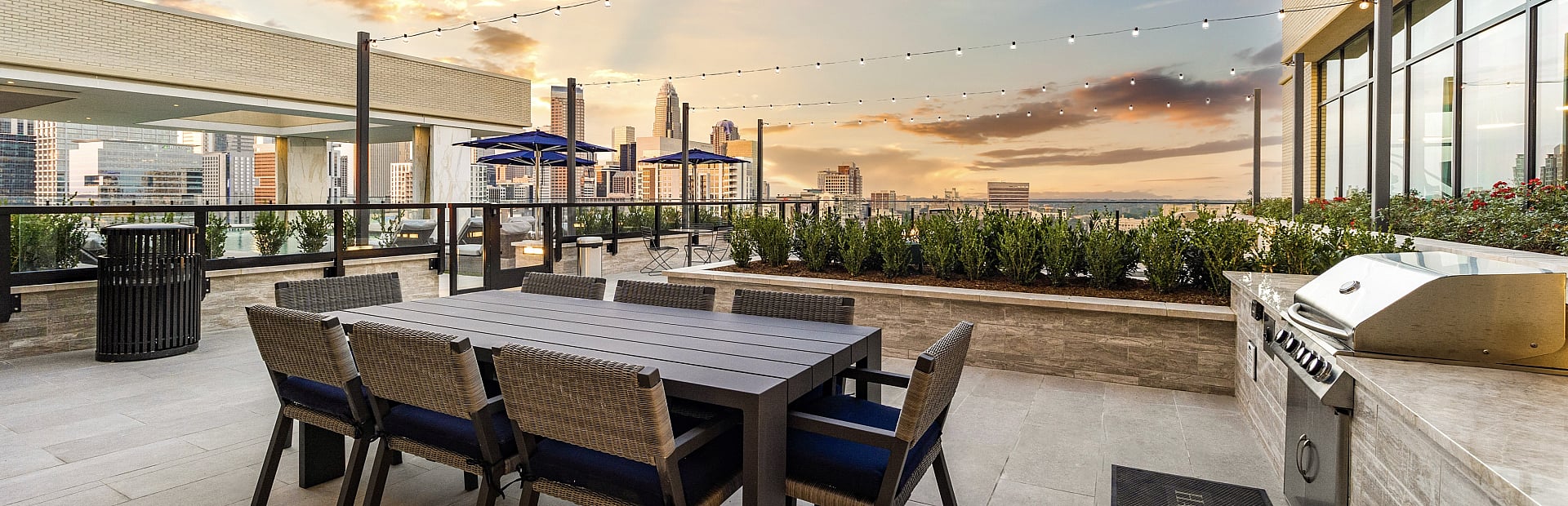 Chic rooftop terrace with stylish dining set, modern grill, and stunning city skyline views at sunset.