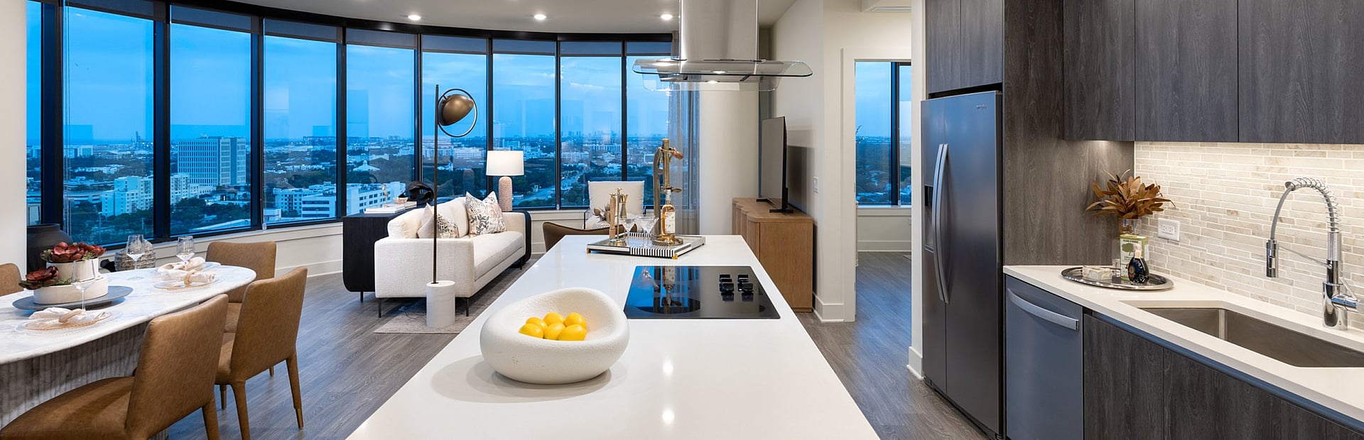 Modern open-concept apartment with panoramic city views, sleek kitchen, and elegant dining area.