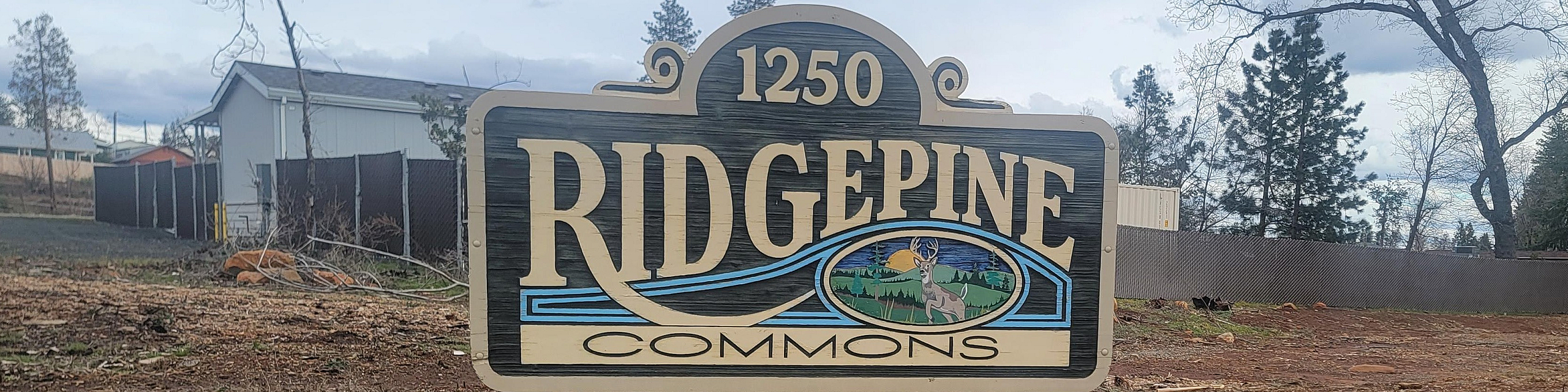 Inviting entrance sign to Ridgepine Commons, set amidst a serene landscape of tall trees, offering a tranquil community atmosphere.