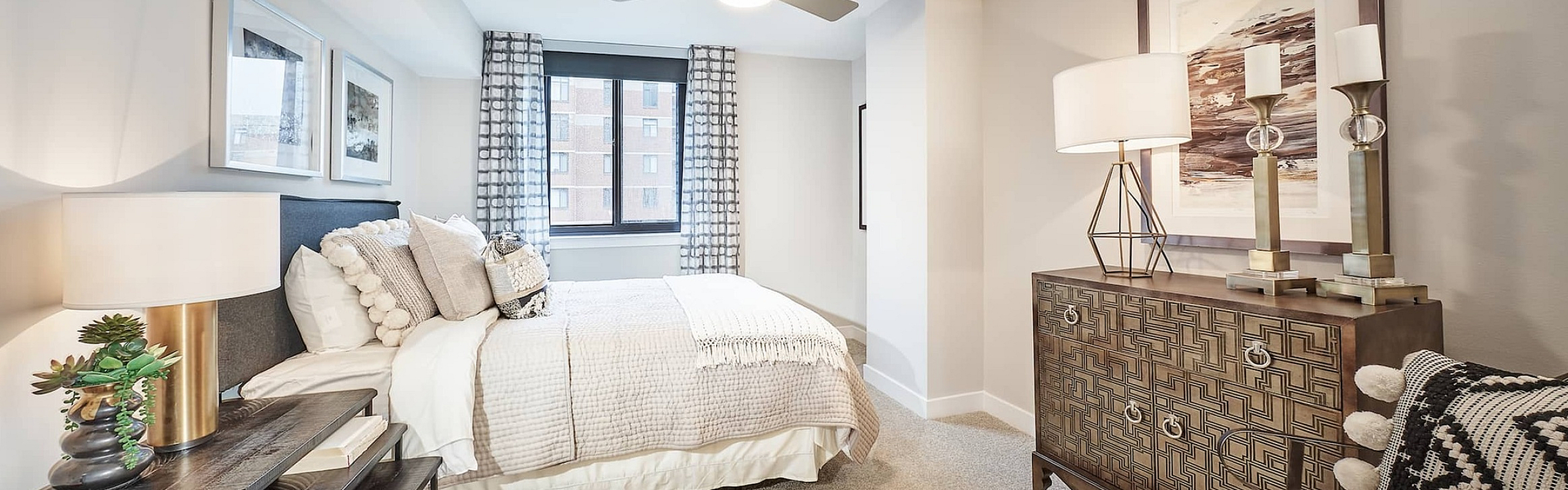 Elegant bedroom with a plush bed, stylish decor, and ample natural light from a large window, perfect for relaxation.
