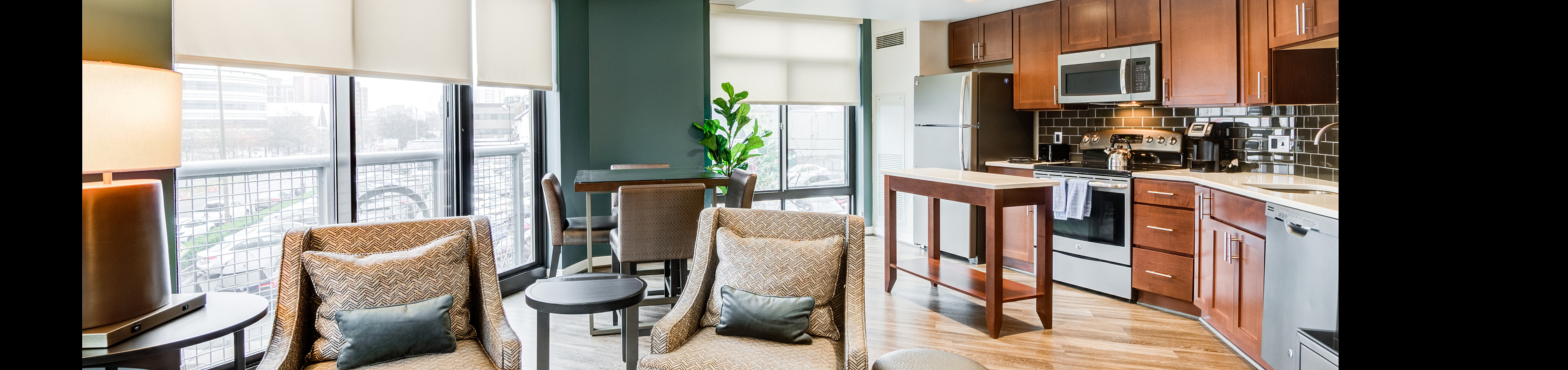 Modern open-plan living area with elegant kitchen, stylish dining space, and cozy seating overlooking city views.