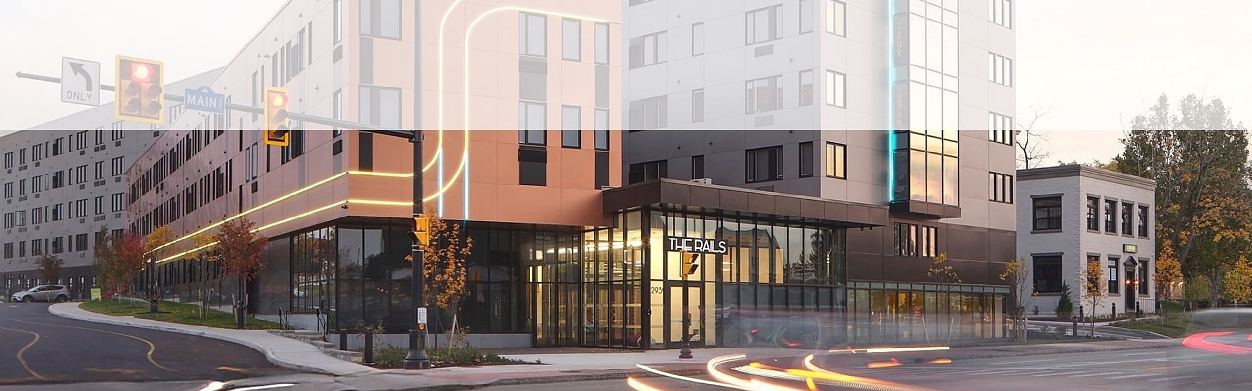 Exterior view of the corner of The Rails building, featuring building lights and windows.